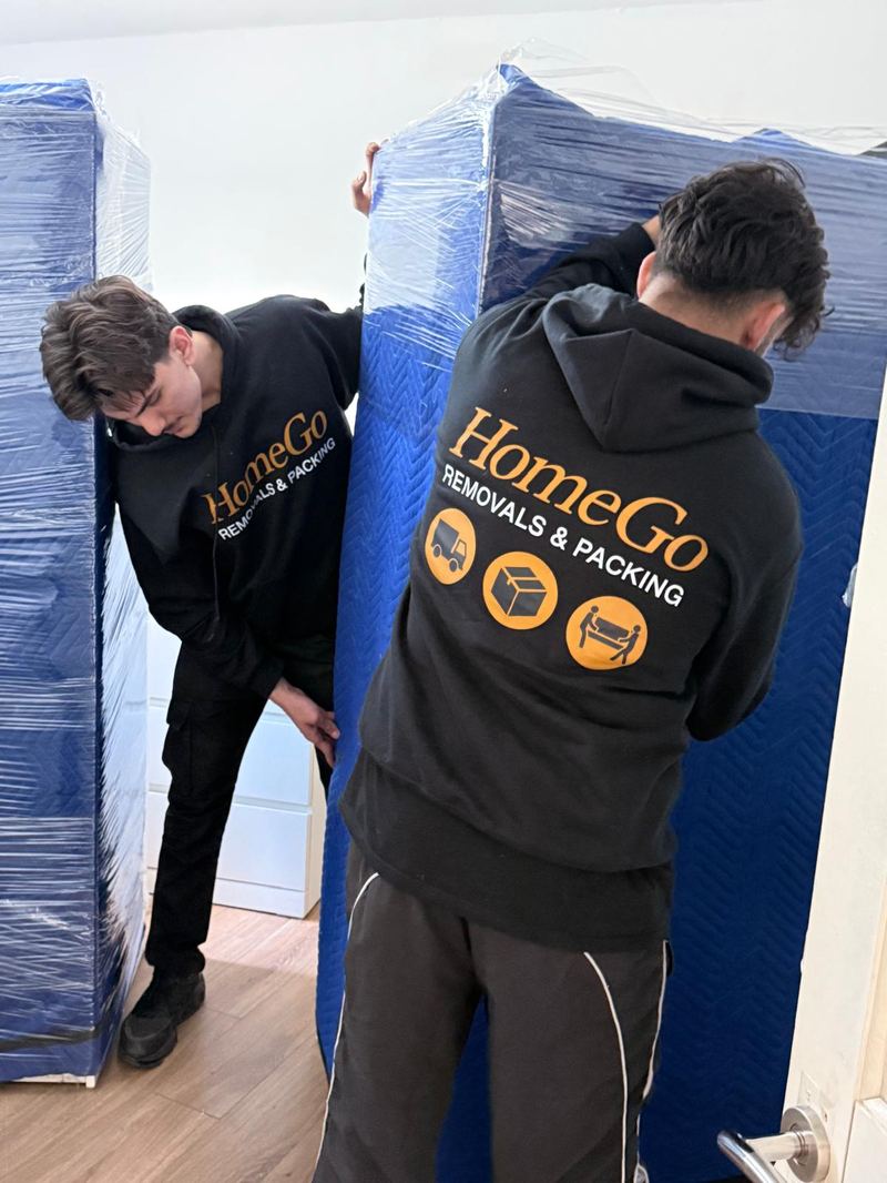 Two HomeGo Removals team members carefully loading professionally-wrapped furniture at a Slough property