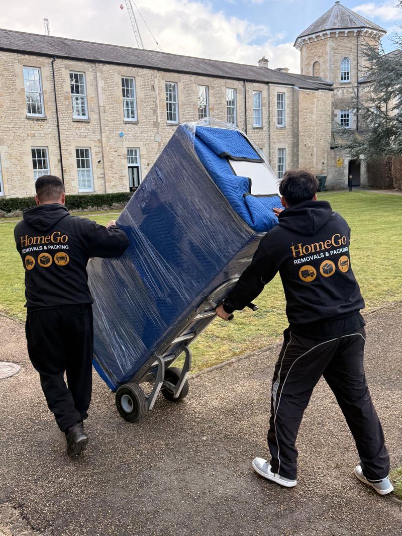 HomeGo Removals crew in branded hoodies wrapping a wardrobe with protective blankets during a house move in Berkshire